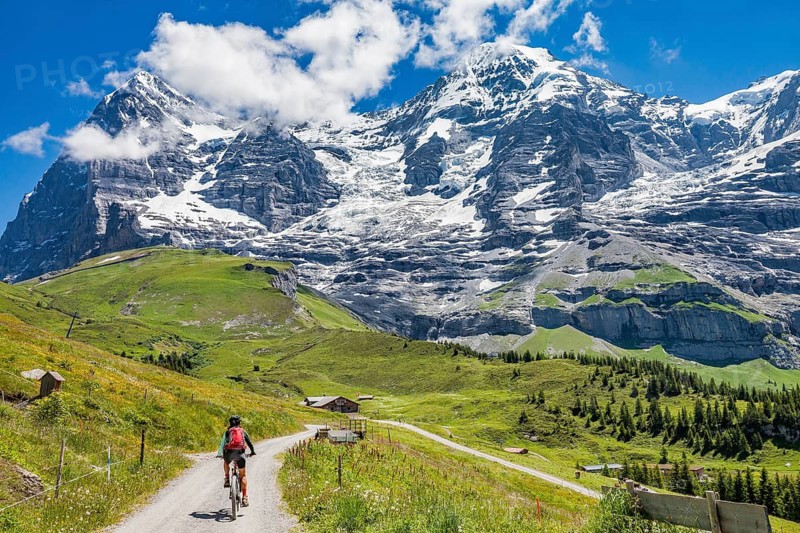 Woman riding her e-mountainbike below the Eiger northface, Jungfrauregion, Grindelwald, Bernese Oberland Switzerland