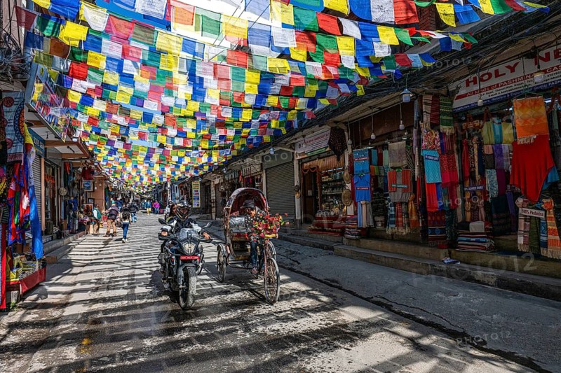 Bicycle rickshaw in a sparsely busy street with prayer flags and souvenir shops, Thamel, Kathmandu, Nepal