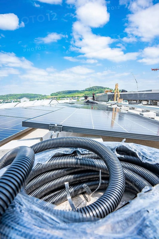 Close-up of cables next to solar panels under a blue sky, PV assembly, Perrot company, Calw, Germany