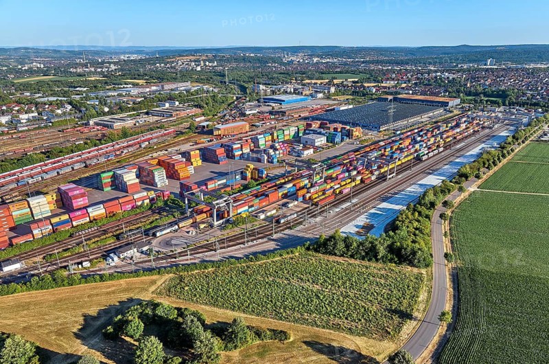 Aerial view of a large container terminal with freight trains, shipping containers, cranes, and rail logistics infrastructure surrounded by farmland. Kornwestheim, Baden-Württemberg, Germany