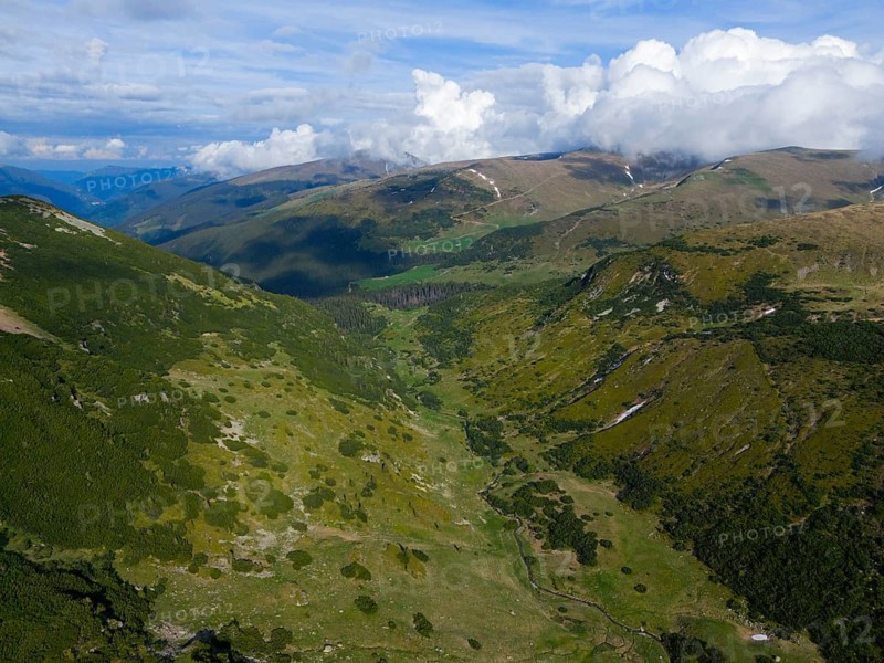 Extensive green mountain landscape with valleys under a dramatic cloudy sky, aerial view, near Rânca, Transalpina High Road, Drum na?ional 67C, national road, Transylvania Alps, South Carpathians, Romania