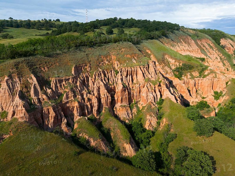 Impressive erosion formations in earthy hills surrounded by lush vegetation under blue sky, aerial view, Râpa Ro?ie, Rapa Rosie, Red Gorge, Nature Reserve, Sebe?, Sebes, Alba County, Transylvania, Romania