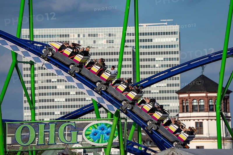 Rheinkirmes in the Rheinwiesen in Düsseldorf-Oberkassel, Alpina Bahn rollercoaster, the Dreischeibenhaus in the back and castle tower in the old town, North Rhine-Westphalia, Germany