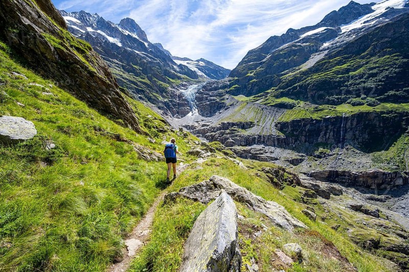 Female mountaineer hiking trail in front of mountain panorama, picturesque high-alpine mountain landscape with Lower Eismeer glacier range, hiking to Schreckhornhütte, Bernese Oberland, Switzerland