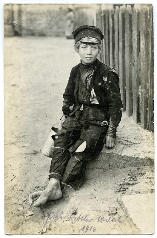 Jewish beggar, boy, Vilnius, Lithuania, poverty, poverty, hunger, orphan, World War I, boy sitting barefoot on sidewalk, wearing poor clothing and cap, atmosphere is calm, 1916