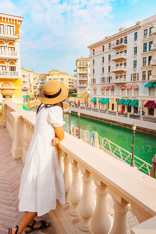 Doha, Qatar - 20th january, 2026: Woman traveler enjoy canal views in Qanat Quartier Pearl Qatar colorful Venice style architecture with canals bridges luxury waterfront lifestyle travel destination