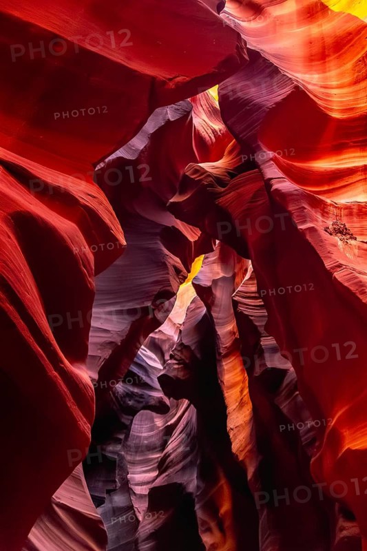 Antelope canyon slot canyon showing colorful ancient sandstone walls carved by water erosion, creating smooth, wavy patterns and contrasting light and shadow features from above