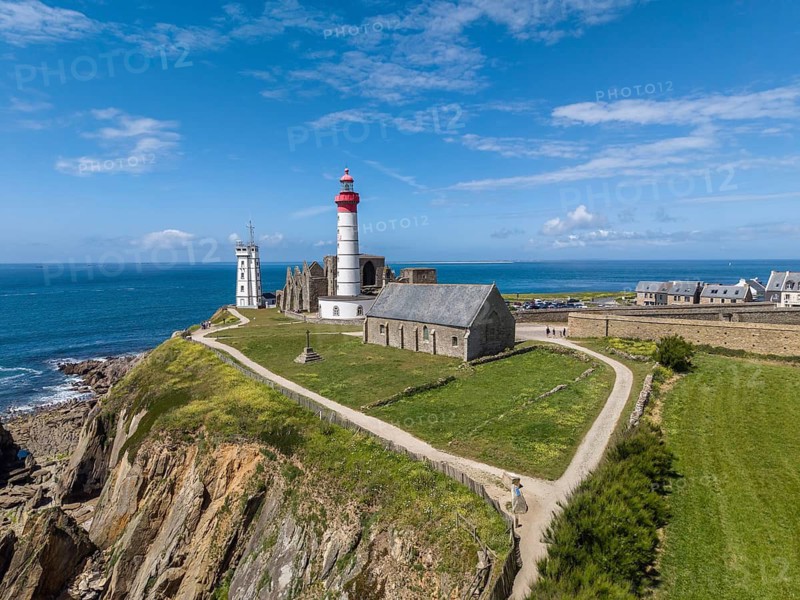 Aerial view of the distinctive red and white lighthouse Phare de Saint-Mathieu on the Breton coast next to the historic church ruins of the former Benedictine Abbey of Saint-Mathieu de Fine-Terre, next to it a white marine signal tower also called Sémaphor, Pointe Saint-Mathieu, Plougonvelin, Finistère department, Brittany region, France
