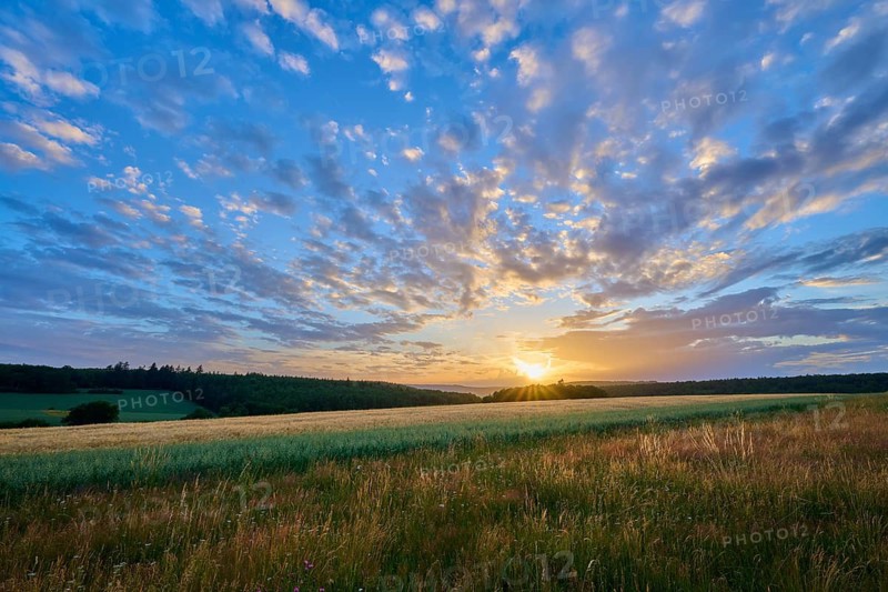 A silent sunset over a wide field with dramatic cloud formations interspersed with orange light, summer, Großheubach, Miltenberg, Spessart, Bavaria, Germany