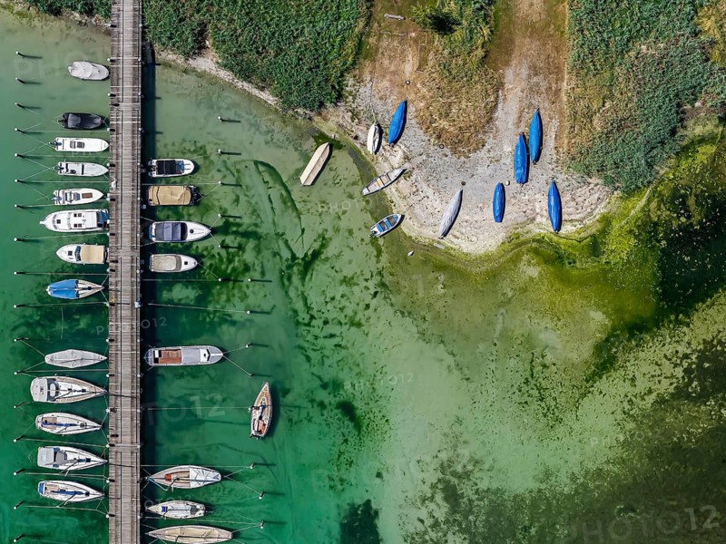Lake Constance shore on the island of Reichenau with boats and swimmers. The bottom of the lake can be seen in many shallow water zones. The water level of Lake Constance is currently low for the time of year. Reichenau, Baden-Württemberg, Germany