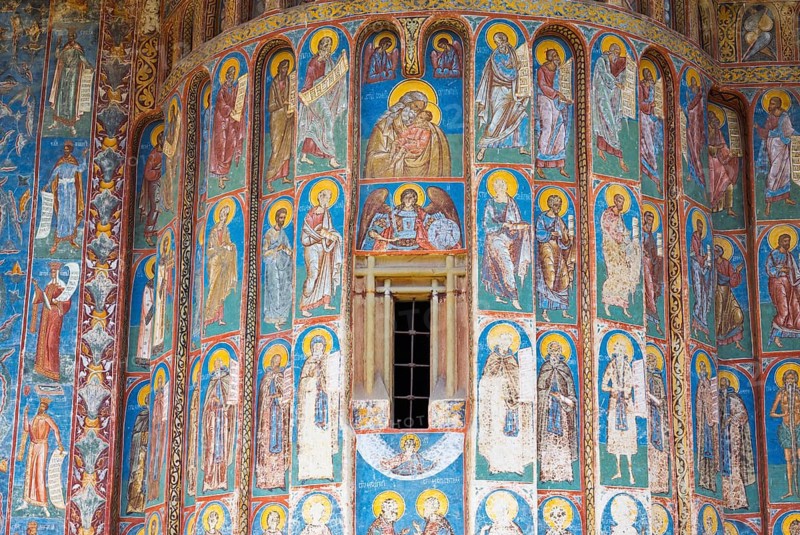 Wall with frescoes of figures of saints and windows, mostly in shades of blue and gold, exterior view, Saint George Monastery, Voronet Monastery, UNESCO World Heritage Site, Suceava District, Bukovina Region, Moldova, Romania