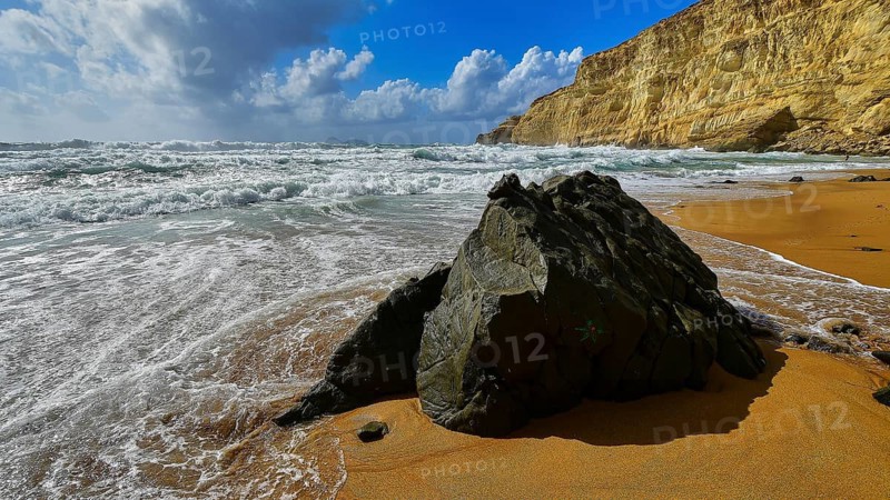 Red Beach, dream beach in the neighboring bay of Matala, large rock on sandy beach with waves and blue and white sky in the background, Matala, south coast, Crete, Greek Islands, Greece