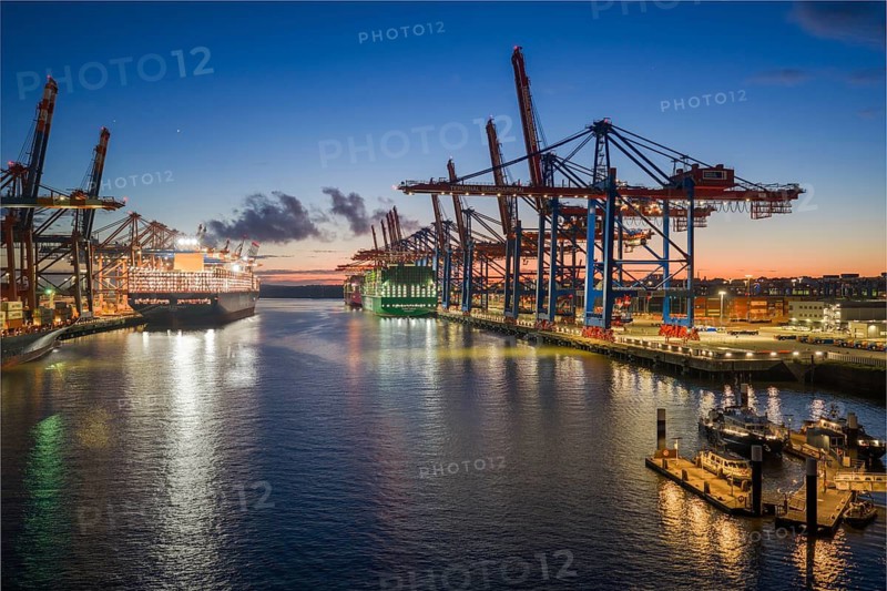 Panoramic aerial view at Waltershof harbour during the Blue Hour with Eurogate Container Terminal Hamburg (CTH) and Container Terminal Burchardkai (CTB) with the brightly lit Ever Meed, Manila Express and Fort Desaix in the background, Hamburg, Germany