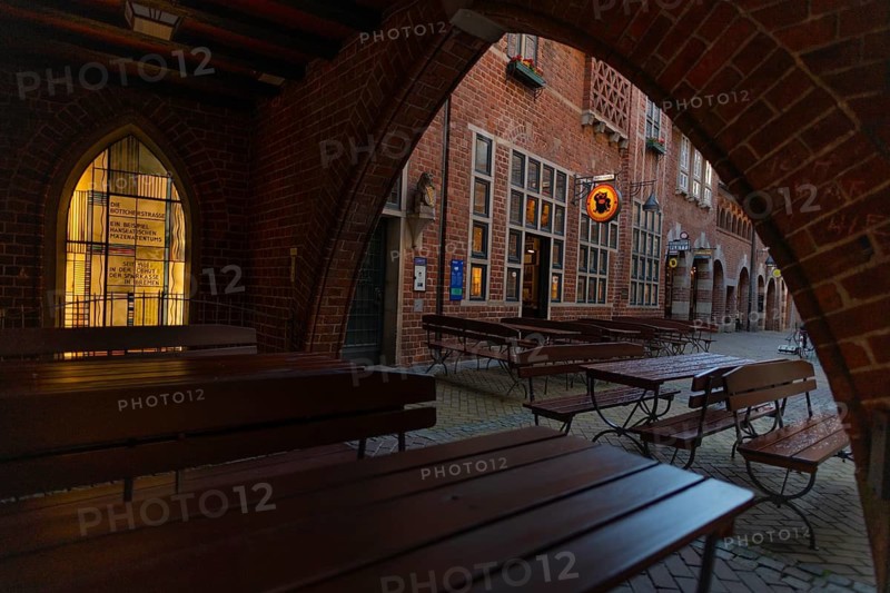 View through the arch of the houses from St. Peter, Böttcherstraße 3-5, cultural monument, historic Böttcherstraße in the old town of the Hanseatic City of Bremen from the 1920s, example of brick expressionism architecture, brick architecture, popular tourist destination, restaurant, outdoor restoration, empty tables and benches, rainy weather, Germany