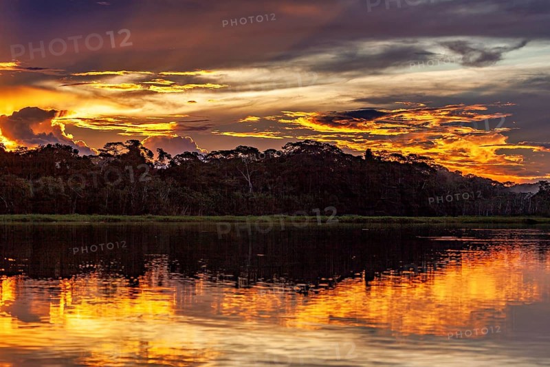 Sunset over a river with dramatic sky and intense reflections, sunset on the Beni River near Rurrenabaque in the Amazon Basin in Bolivia