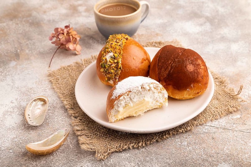 Maritozzo traditional Italian bun dessert, cup of coffee, on brown concrete background with linen textile, close up, side view
