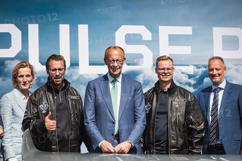 Friedrich Merz between Florian Seibel and Sven Kruck (both from Quantum Systems) at the presentation of the PULS P19 autonomous drone during the Chancellor's tour of the ILA (International Aerospace Exhibition) on 10 June 2026 at the Berlin-Schönefeld Exhibition Centre