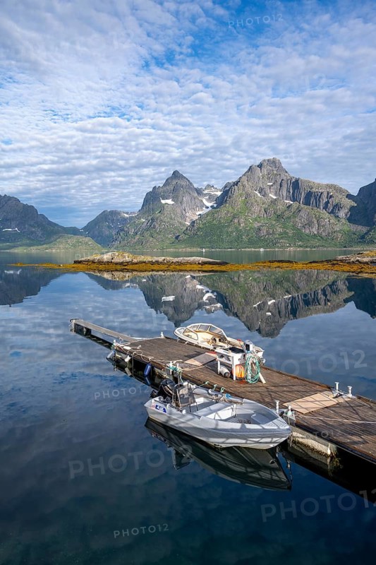 Boats on a jetty, picturesque fjord landscape at Raftsund fjord, mountains reflected in the water, Vesterålen, Norway