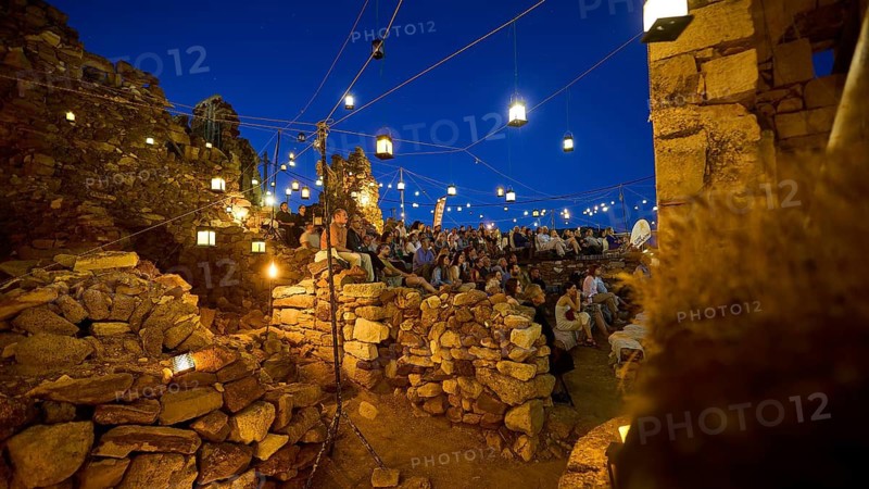 Open-air cinema, people gathered in a rocky area at night under twinkling lights, Kastro, old castle above Chorio, Kimolos, Cyclades, Greek Islands, Greece