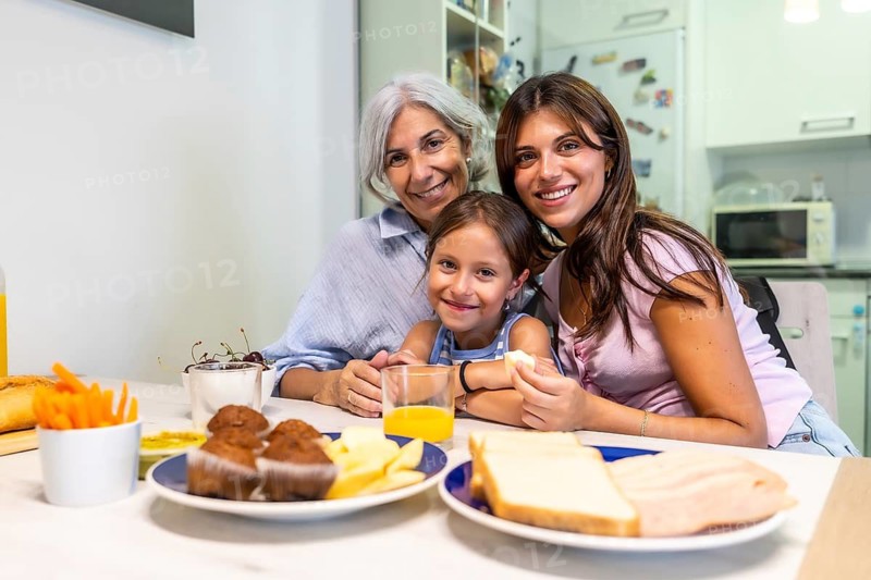 Grandmother, mother, and daughter sharing a happy moment during breakfast at home, depicting family bonds, love, and multi generational connection around a table filled with food