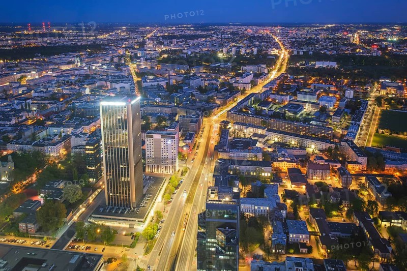Broad view across the Warsaw skyline in Poland with skyscrapers, city lights, nightfall color, blue hour twilight and evening glow