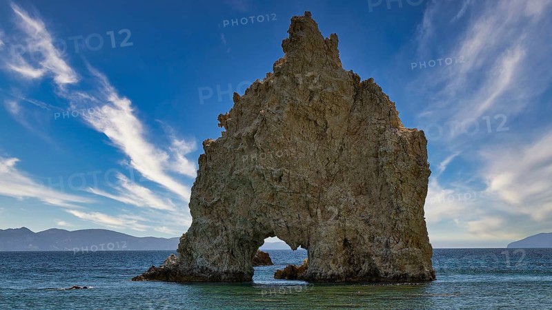 A large, jagged rock juts out of the sea under a clear blue sky, Aspragremna, White Cliffs, Mavorspilia Beach, Kimolos Island, Kimolos, Cyclades, Greek Islands, Greece
