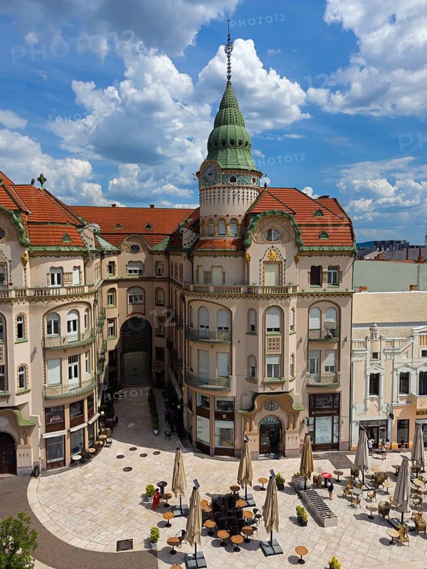Baroque building view with green tower and red roofs surrounded by shops and cafe under cloudy sky, aerial view, Black Eagle Palace, Piata Unirii, Unity Square, Oradea, Oradea, Oradea, Bihor district, Kreischland, Transylvania, Romania