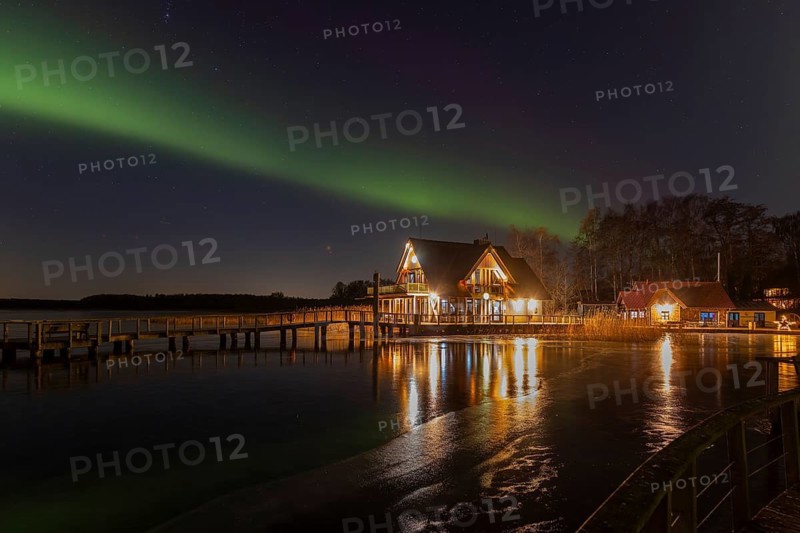 Illuminated restaurant, jetty and Northern Lights, Aurora borealis over Lake Hemmelsdorf, Hemmelsdorfer See near Lübeck, Schleswig-Holstein, Germany