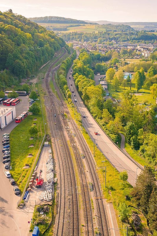 Railway line in mountainous area with forests, roads and cars in sunny weather, electrification of the Hochrheinbahn, conversion of the train station, Waldshut, Tiengen, Germany