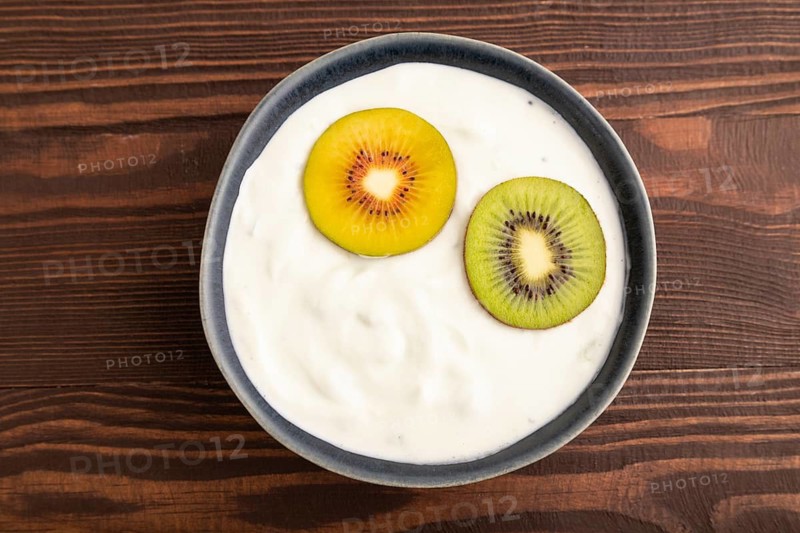 Yogurt, with kiwi in blue bowl on brown wooden background, top view, flat lay, close up, minimalism