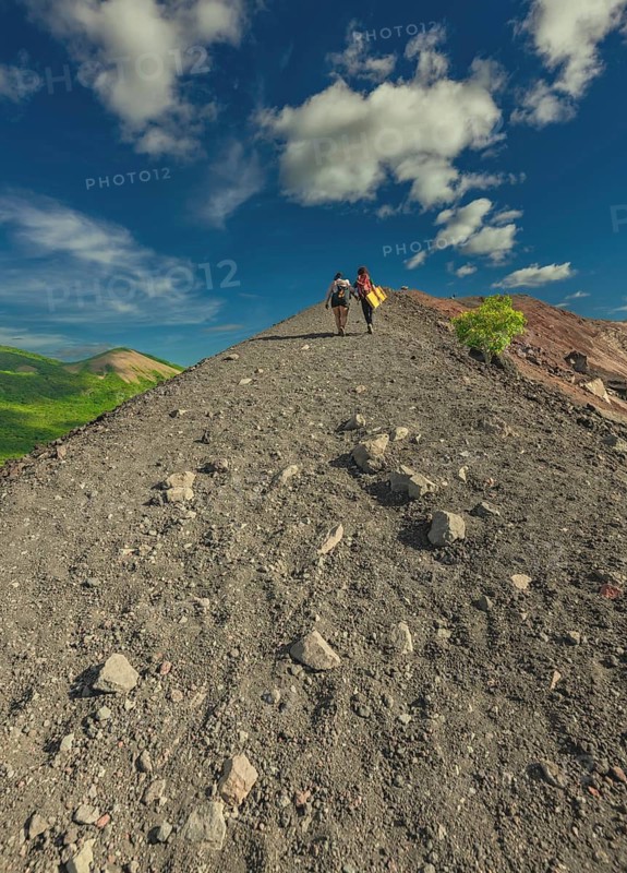 Rear view of two tourists climbing Cerro Negro with a beautiful landscape in the background. Landscape of tourists hiking to the summit of Cerro Negro volcano
