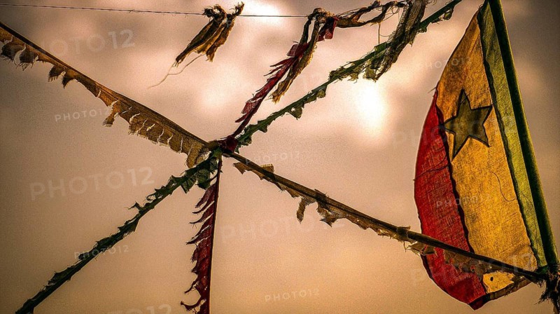 Colourful flags flying on a rope, flag of Senegal, Senegalese flag against an orange sky at sunset, traveling in Senegal