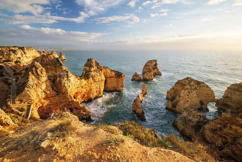 Golden sunrise light over Ponte da Piedade in Lagos, Algarve, Portugal, with ocean cliffs, sea stacks, Atlantic water, and rocky coast