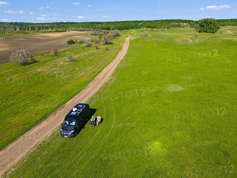 A camper stands next to a dirt road on a green field under a blue sky, aerial view, motorhome, landscape near Braniste, Braniste, Hundred Hills Landscape Reserve, Rî?cani, Republic of Moldova, Moldova