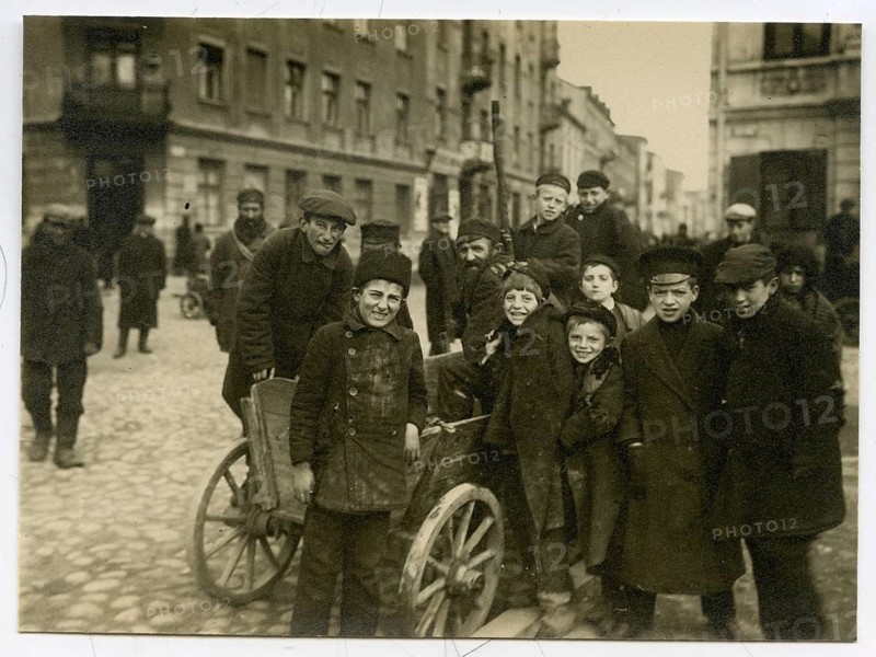 Jews, young men, traders, group of boys, shtetl, eastern Poland, Galicia, some smiling, gathered around a cart in the old town, atmosphere is lively, around 1916