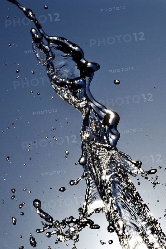 Water frozen by short exposure moving in backlight in front of the sun