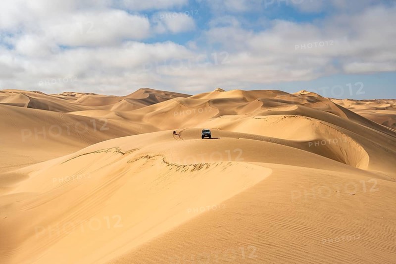 Off-road vehicle between sand dunes, sea of dunes, sandy desert, impressive desert landscape, Namib Naukluft Park, Namib Desert, Namibia