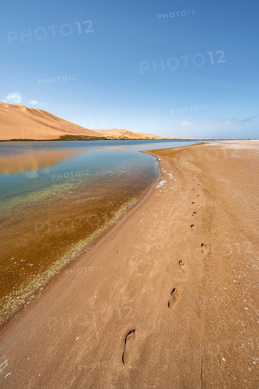 Footprints in sand, sand dunes and lagoon at Sandwich Harbour, Namib Naukluft Park, Namib Desert, Namibia