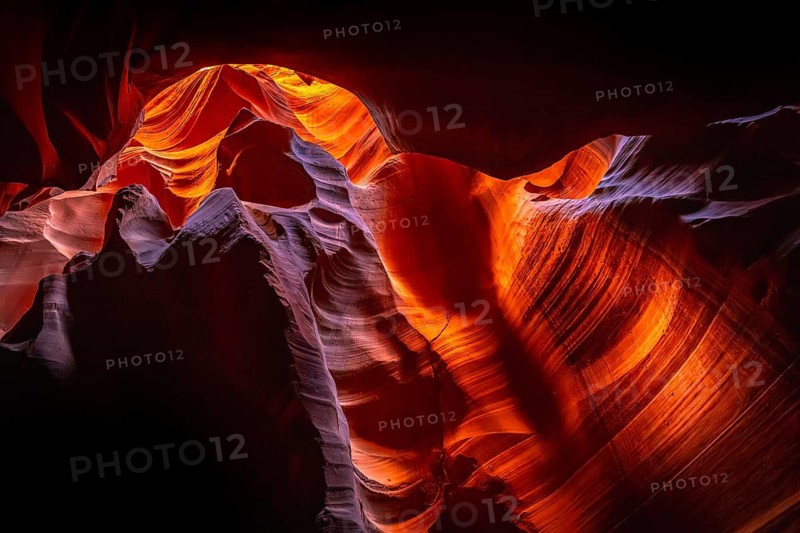 Antelope canyon slot canyon interior showing carved sandstone walls, receiving a light beam illuminating the vibrant orange, purple, and red rock formations