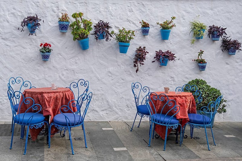 Street cafe with blue outdoor furniture and blue flower pots on a white wall in a Mediterranean style, Mijas, Andalusia, Spain
