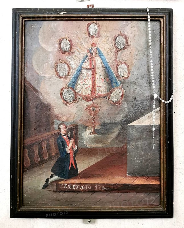 An 18th-century votive painting in the monastery church at Mönchsdeggingen, the former monastery of the Mariannhill Missionaries, near Nördlingen on the southern edge of the Ries region, in the Donau-Ries district, Swabia, Bavaria, Germany. Depiction of a kneeling figure praying to an image of the Mother of God with Child (miraculous image) within a cloud