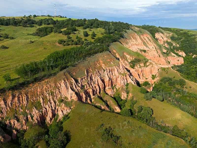 Red erosion rocks on grassy hills with thick vegetation and sky in the background, aerial view, Râpa Ro?ie, Rapa Rosie, Red Gorge, Nature Reserve, Sebe?, Alba County, Transylvania, Romania