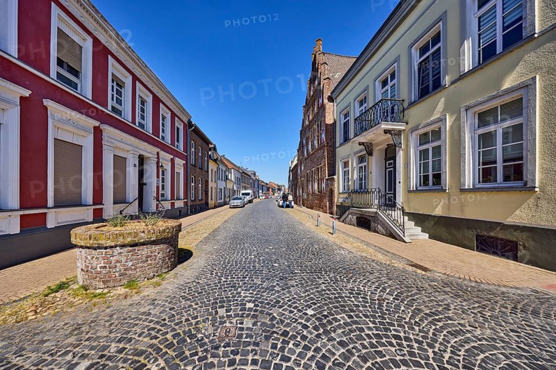 Fountain wall, historic residential building, houses, historic city center, sidewalk, street made of paving stones, parking strip with cars, blue sky, cloudless, Kesselstraße, Kalkar, Kleve district, North Rhine-Westphalia, Germany