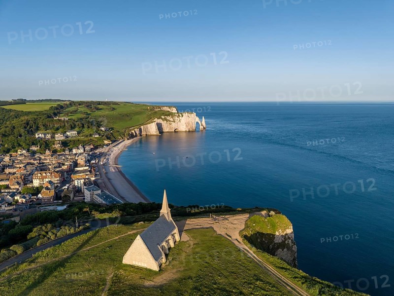 Aerial view of the Notre Dame de la Garde chapel after sunrise at the Falaise d'Amont viewpoint, on the right the coastal town of Étretat with the beach, on the horizon the Porte d'Aval rock formation, Étretat, Alabaster Coast, La Côte d'Albâtre, chalk cliffs, English Channel, Seine-Maritime, Normandy, France