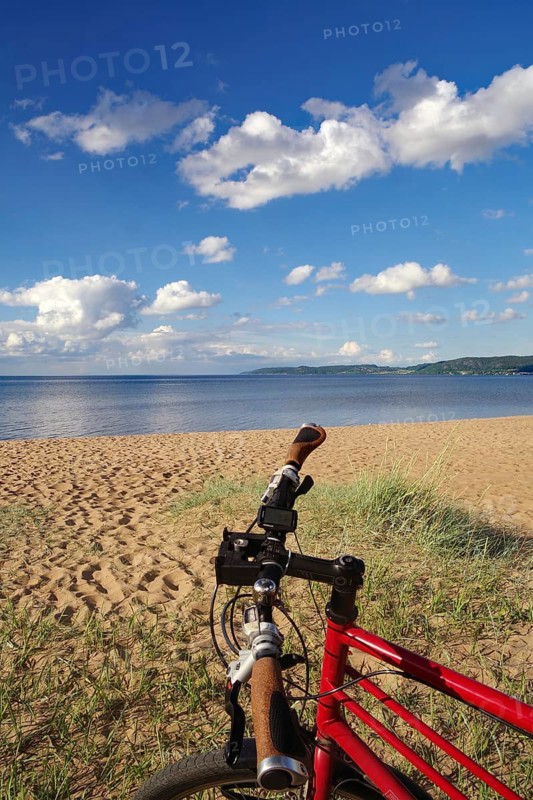 Red bike in front of a beach with a view of the sea and a clear sky, bicycle tours, cycle tourism, Lake Vättern, Jönköping, Sweden