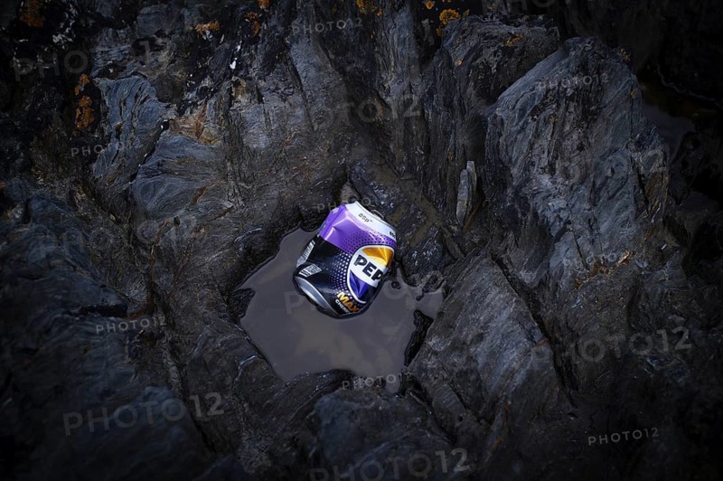 Environmental pollution, trash, empty tin can PEPSI, beverage can, dented, carelessly lying between rocks on the beach, Pennance Point, rocky coast, Falmouth Bay, Cornwall, England, Great Britain, Great Britain