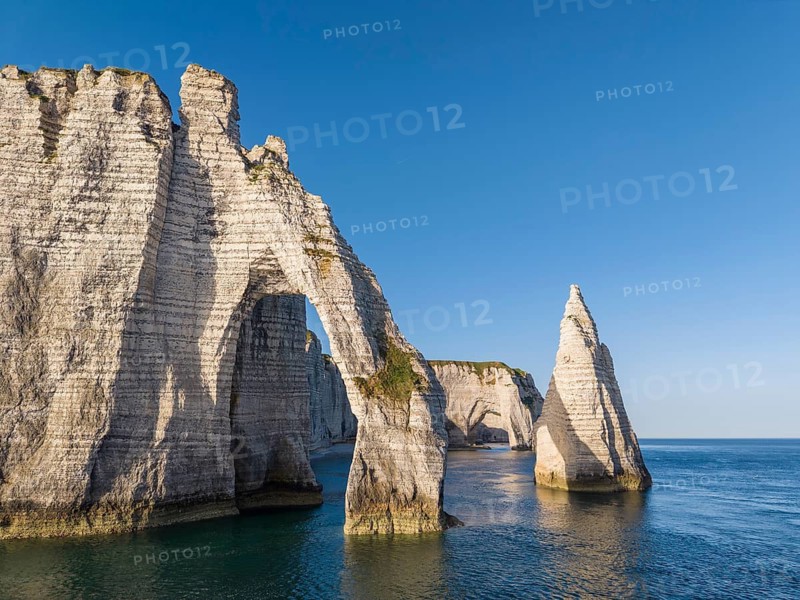 Aerial view of the Porte d'Aval rock formation with the free-standing Aiguille d'Étretat rock pin in the morning sun, well-known sights and natural beauty on the chalk coast, behind it the La Manneporte rock gate, Étretat, Alabaster Coast, La Côte d'Albâtre, chalk cliffs, English Channel, Seine-Maritime, Normandy, France