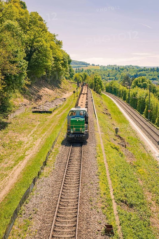A green train on a railway line surrounded by trees and blooming nature, electrification of the Hochrheinbahn, conversion of the station, Waldshut, Tiengen, Germany