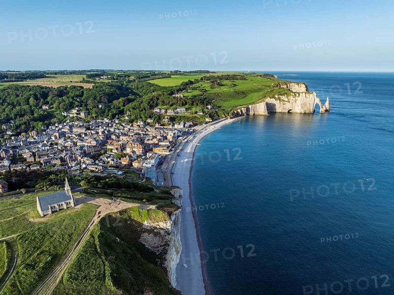Aerial view of the Notre Dame de la Garde chapel after sunrise at the Falaise d'Amont viewpoint, on the right the coastal town of Étretat with the beach, on the horizon the Porte d'Aval rock formation, Étretat, Alabaster Coast, La Côte d'Albâtre, chalk cliffs, English Channel, Seine-Maritime, Normandy, France