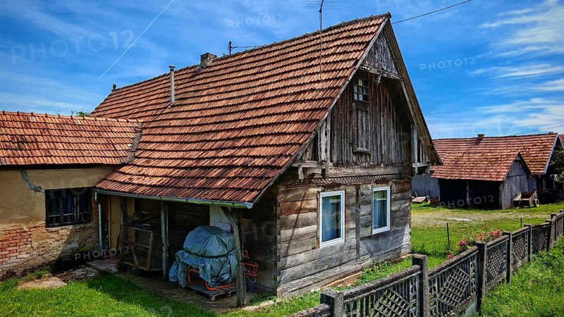 Old, traditional wooden house with adjacent barn and tiled roof, rural and rustic ambiance, Croatia